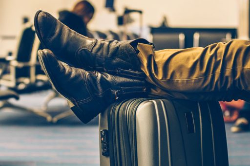 Men's feet resting on his suitcase while he is waiting for his delayed flight