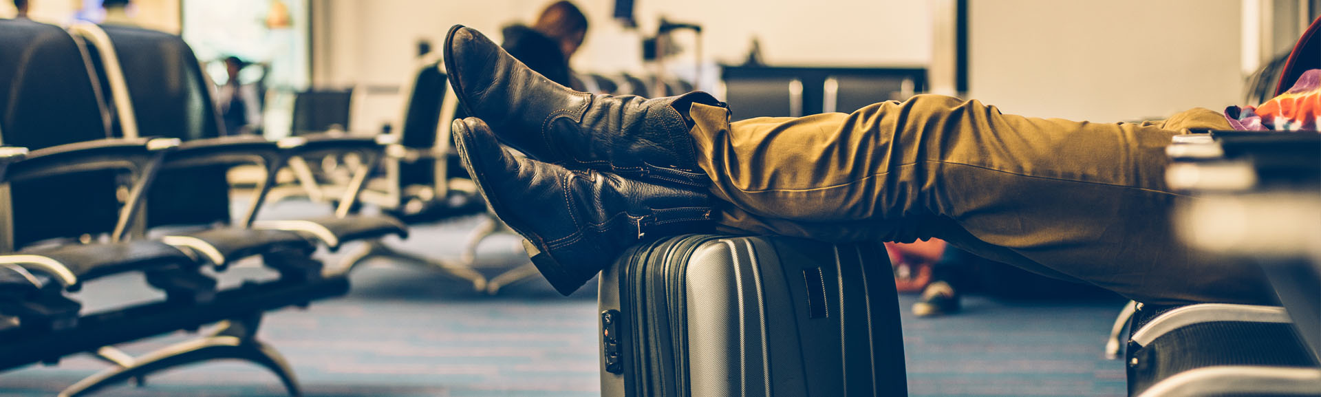 Men's feet resting on his suitcase while he is waiting for his delayed flight