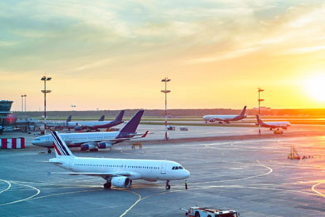 Grounded airplanes on tarmac against the setting sun