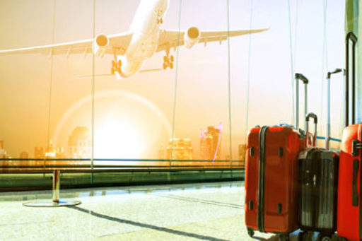 Airplane taking off with three suitcases inside the airport in the foreground