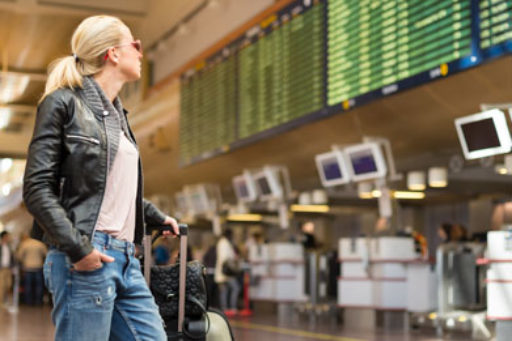 Woman looking at flight departure board at airport.