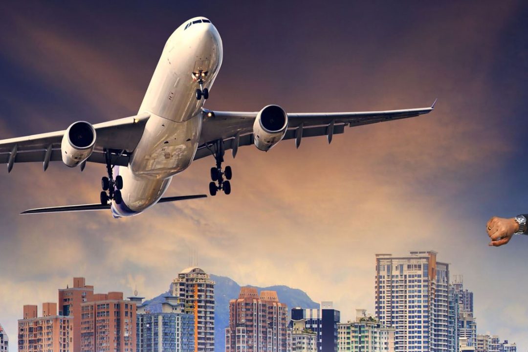 Man checking his watch with a departing airplane about to fly over him
