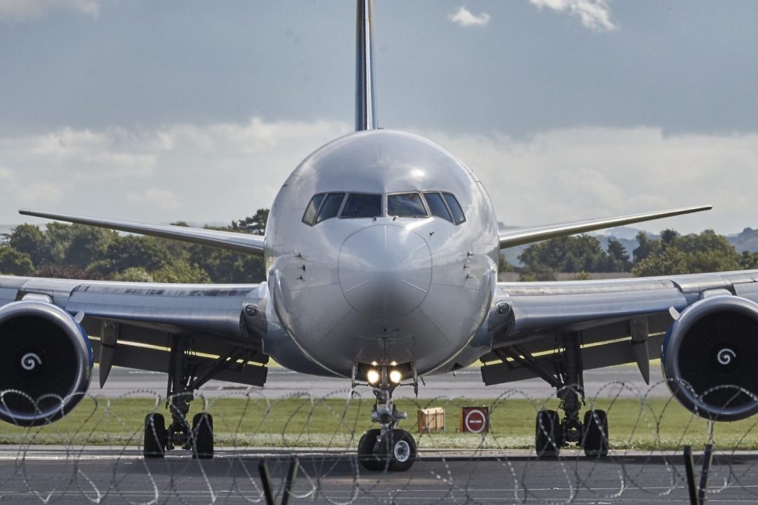 Frontal view of airplane with barbed wire fence in the foreground.