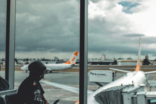 Person sitting at airport window with delayed flight in the background