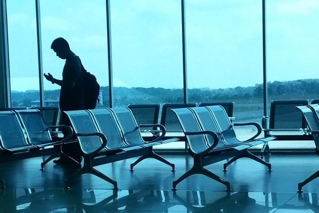 Man's silhouette walking by empty seats at airport